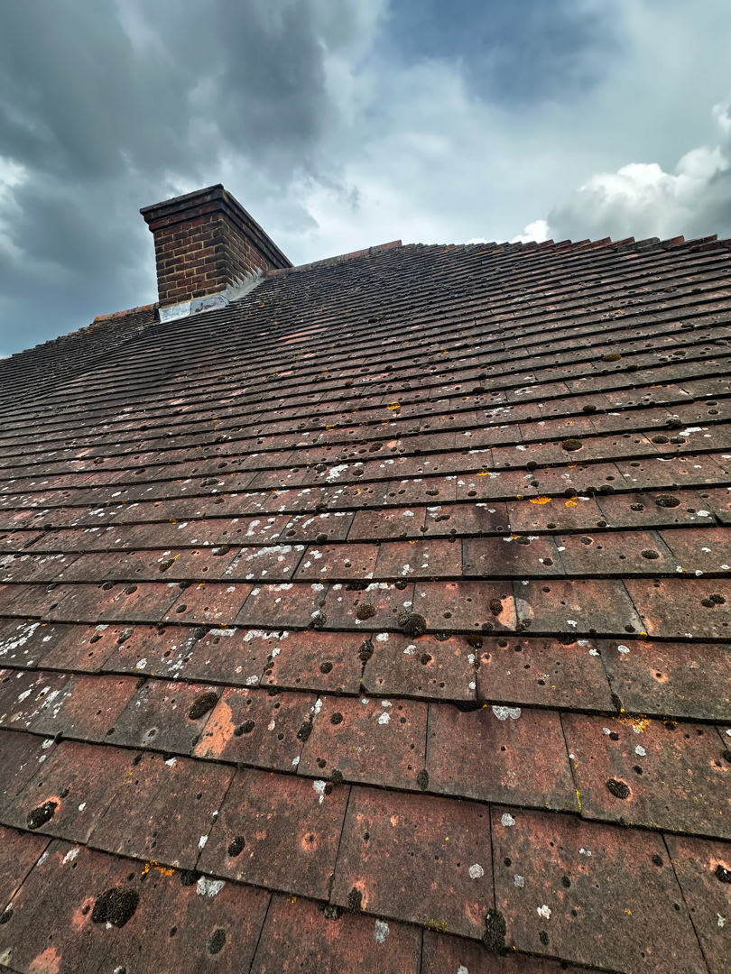 Roofer repairing high rise roof looking over London