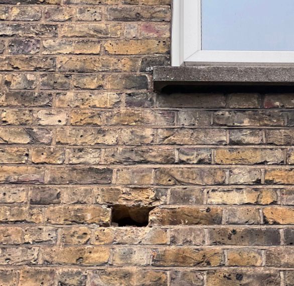 A missing brick on the side of a building.