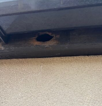 A before photo of a black fascia board with a hole in it.