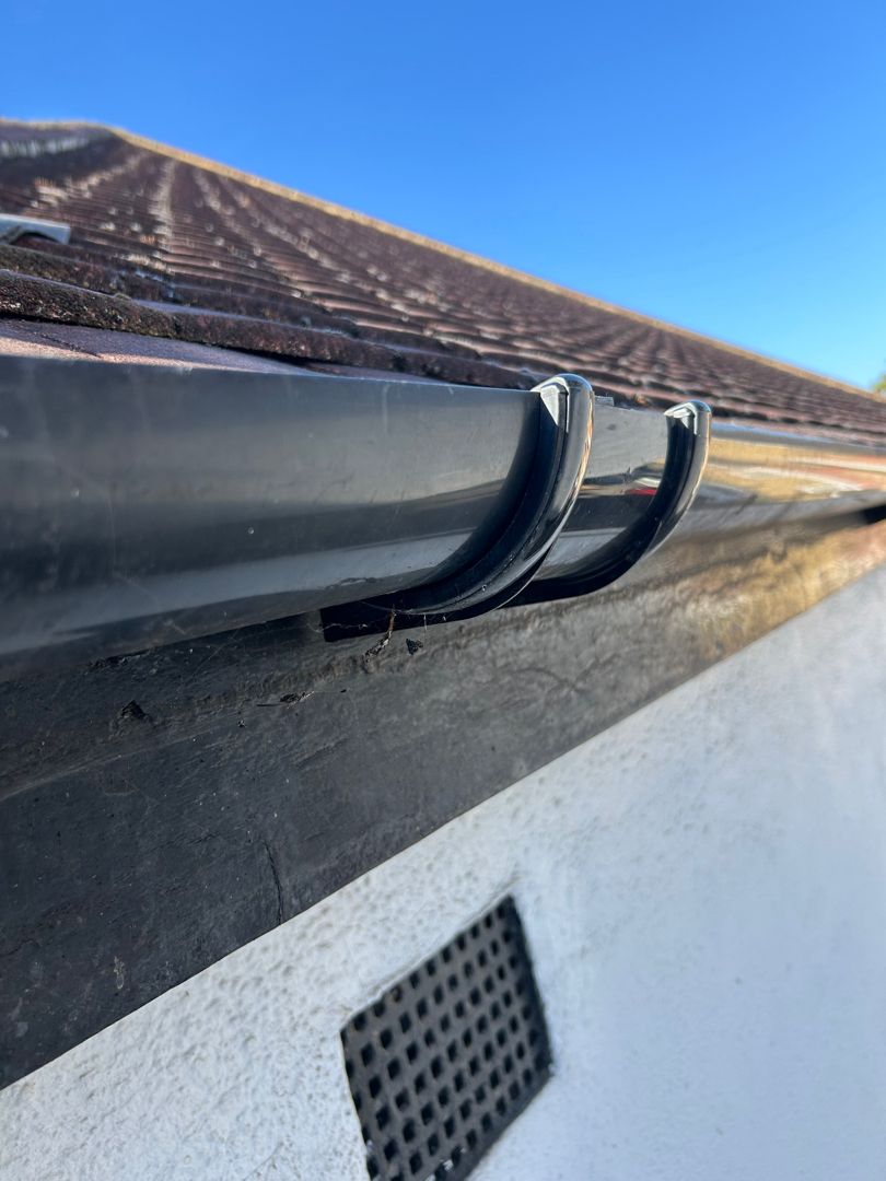 A black UPVC downpipe union that has been repaired.