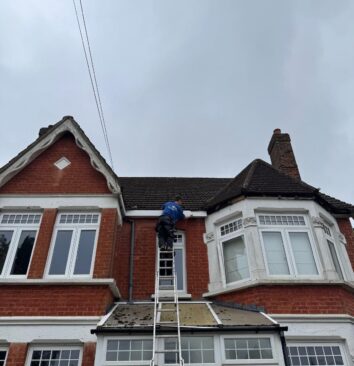 Roofer installing a white fascia board to a residential property.
