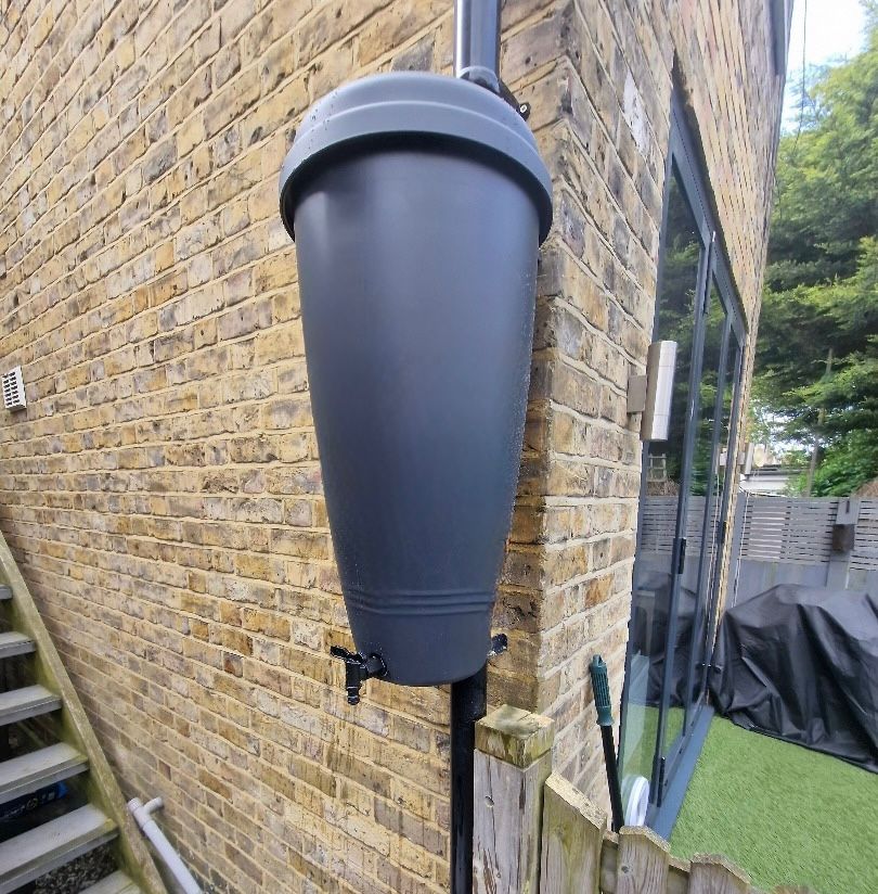 A newly installed water butt that has been fixed to the exterior wall.