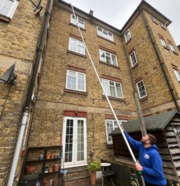 A Sam's Gutters & Roofs technician using a Sky Vac system to clear the gutters on a 4 storey London residential building.