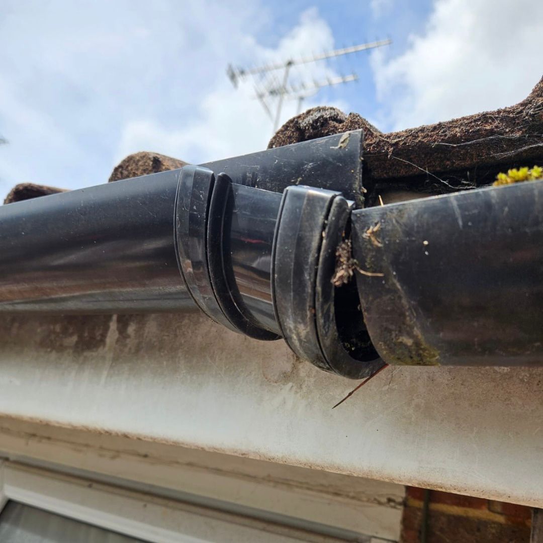 A broken black UPVC gutter where the gutter union has come away from the gutter.