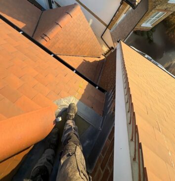 Roofing technician standing on top of commercial building roof looking down.