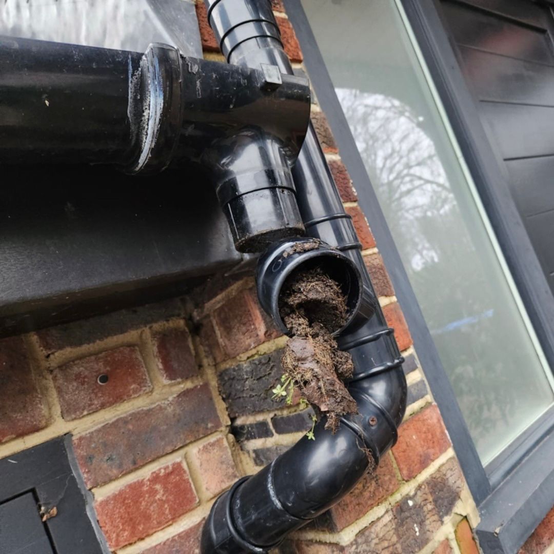Shows a black upvc downpipe that has been taken apart revealing a blockage inside.