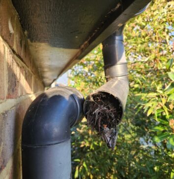 A black UPVC downpipe which has been taken apart to show a blockage.