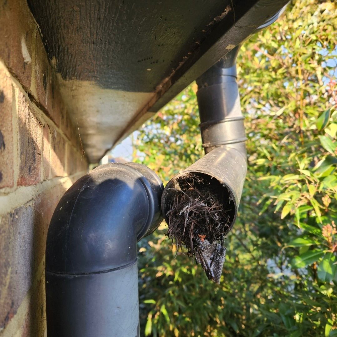 A black UPVC downpipe which has been taken apart to show a blockage.