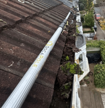 Clearing gutter filled with leaves and debris.
