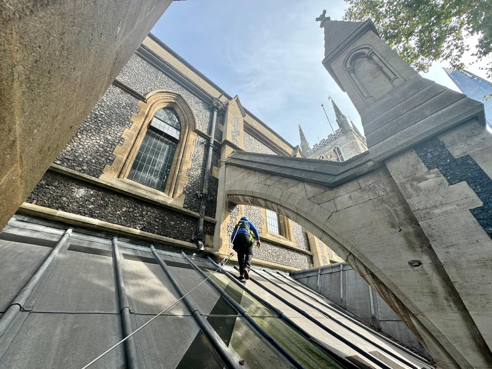 Roofing technician in harness on cathedral roof.