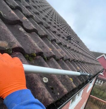 Clearing gutter filled with leaves and debris.