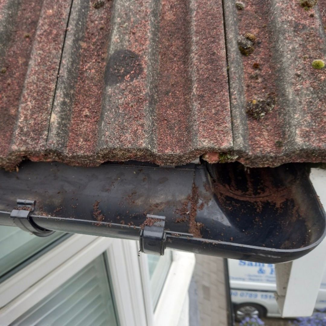 An after photo of a black UPVC gutter corner that has been cleared of leaves and debris.