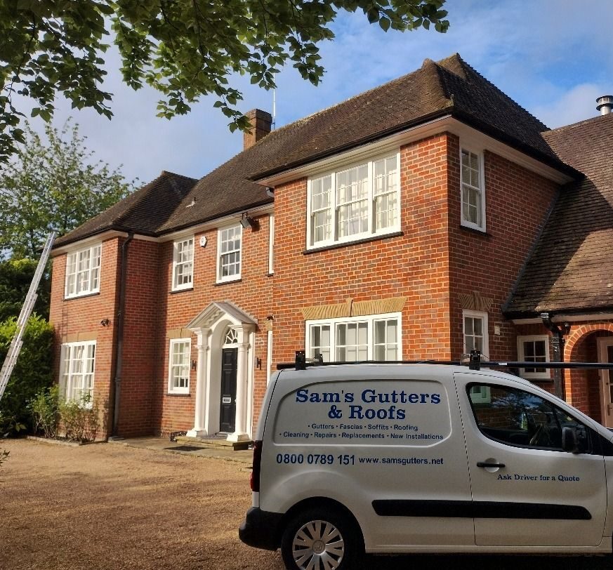 A Sam's Gutters & Roofs company vehicle parked outside a residential property.