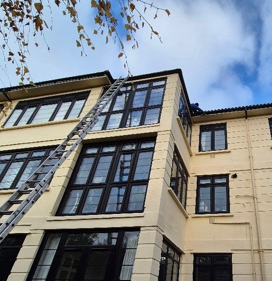 A ladder leaning against a 4 storey building.