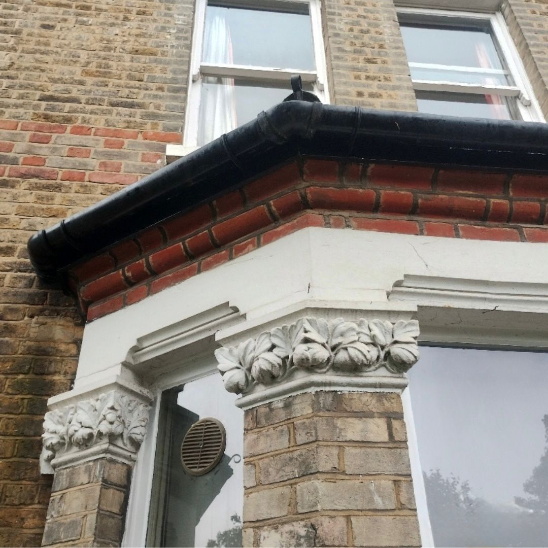 A newly installed black UPVC gutter on a bay window.