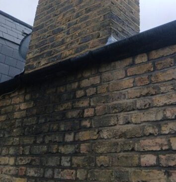 A damp patch on the side of a bricked residential building.
