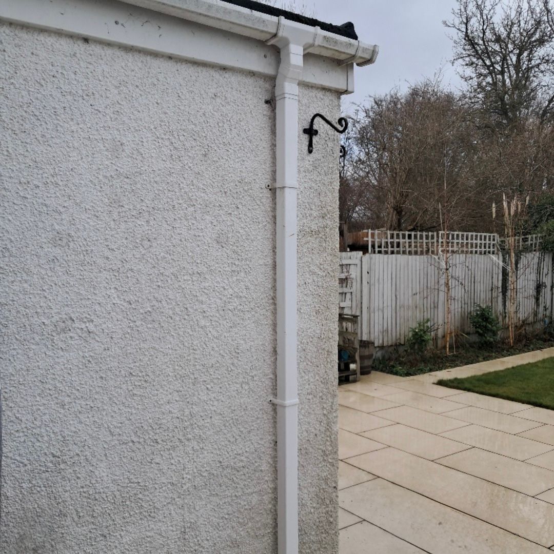 A newly installed white UPVC downpipe on a white property.