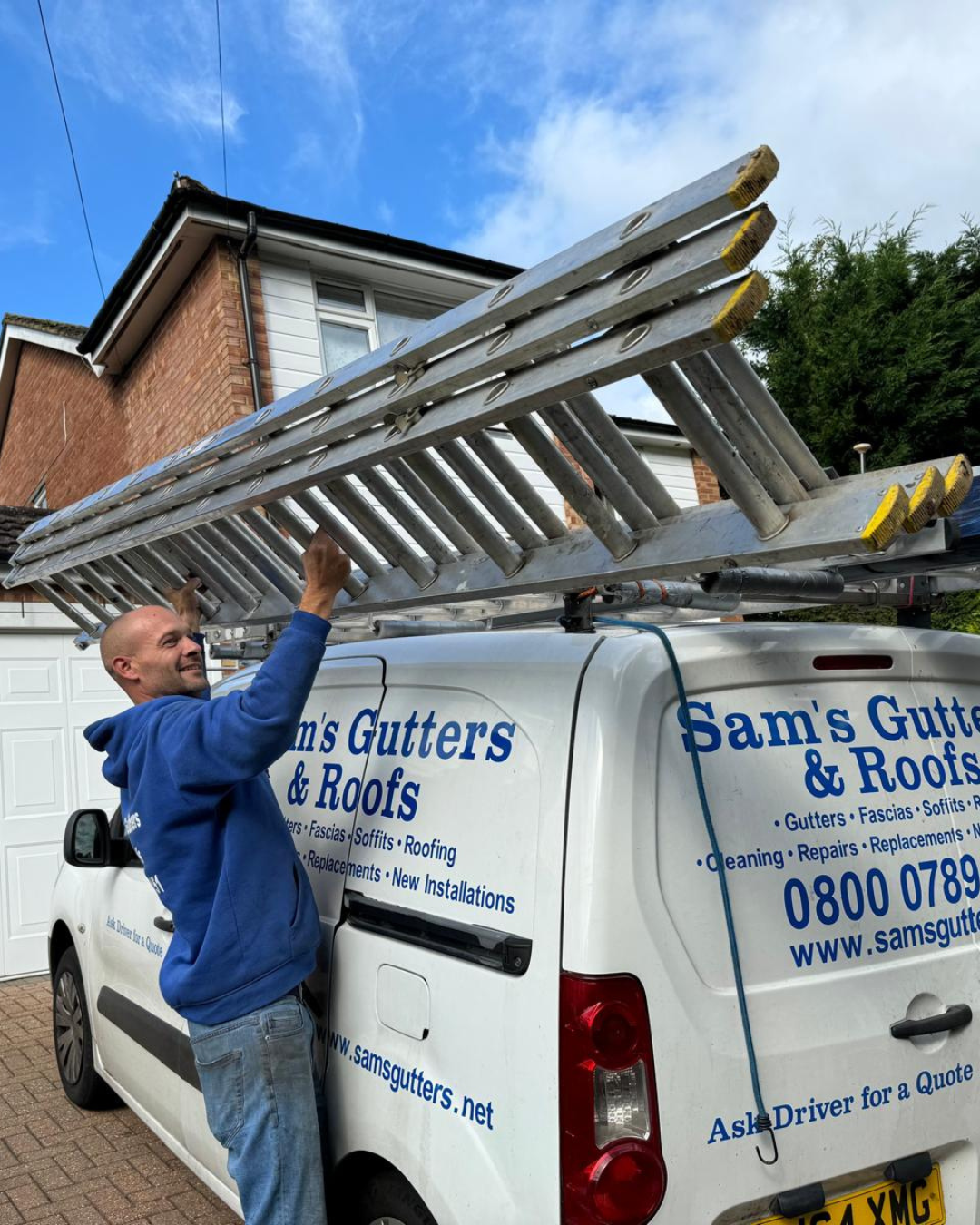 Roofer removing ladder from a company branded white van.