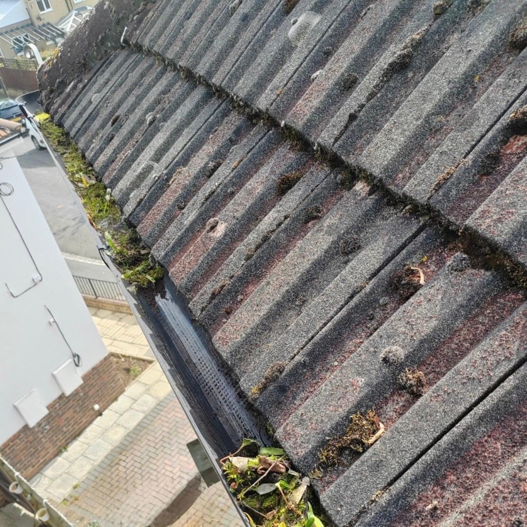 Showing a gutter that has been partly cleared but still partly full of debris.