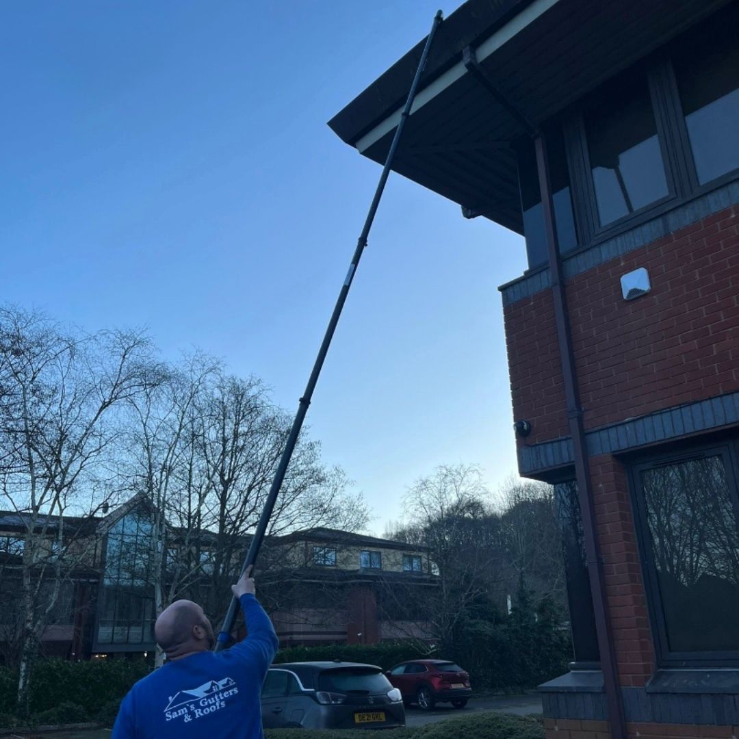 Photo of Sam's Gutters cleaning a commercial building roof from the ground.
