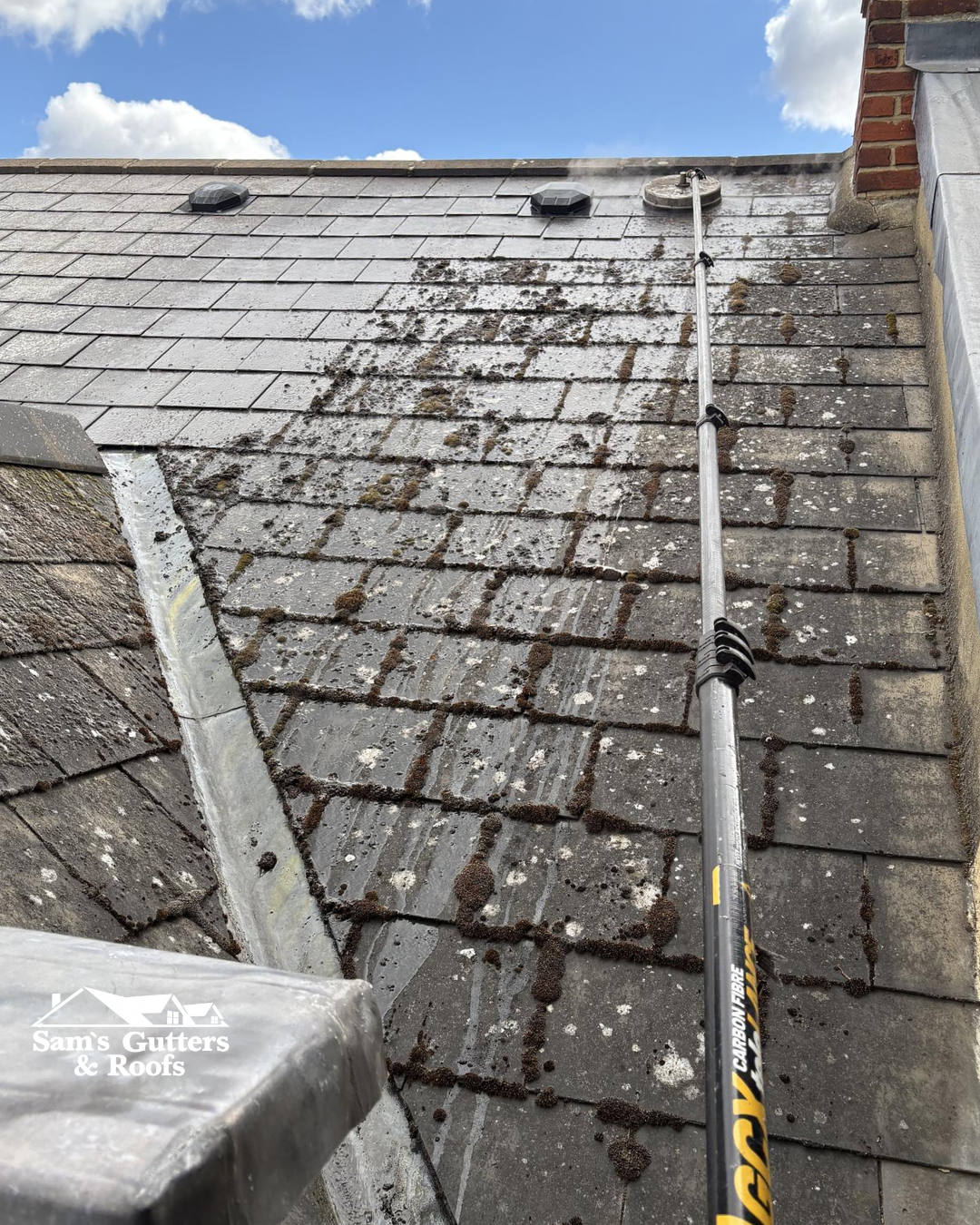 A member of Sam's Gutters cleaning a residential roof for autumn.